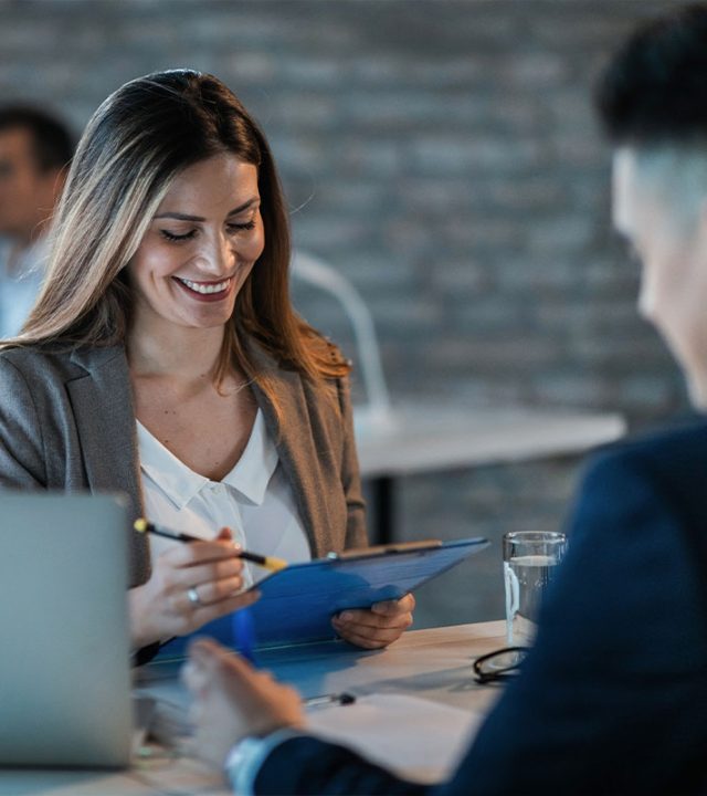 young-happy-businesswoman-reading-reports-while-going-through-paperwork-working-with-colleague-office